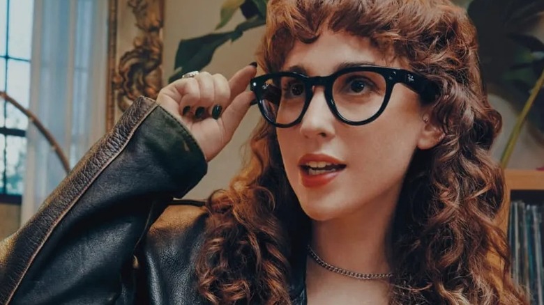 Woman wearing black Ray-Ban Meta glasses and holding the frame