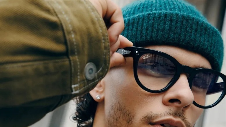 Man wearing Ray-Ban Meta glasses holding frame with one hand