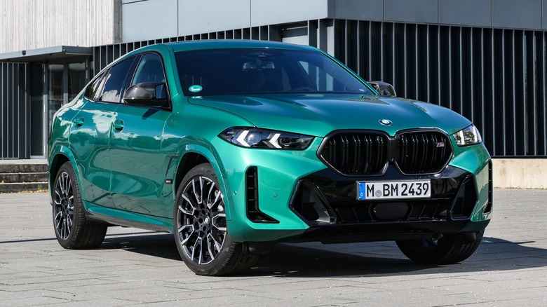 Isle of Man Green Metallic BMW X6 M60i parked on a paved surface in front of a building