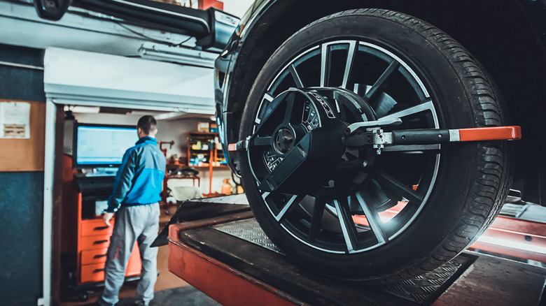 A mechanic working on car's wheel alignment.