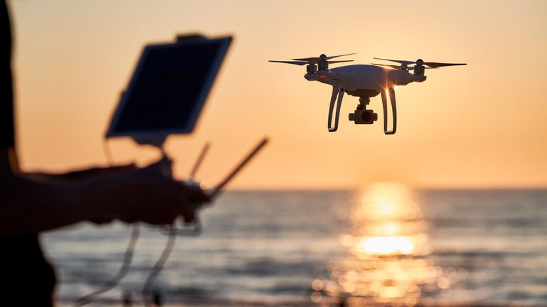 Drone operated by a man, flying by the sea