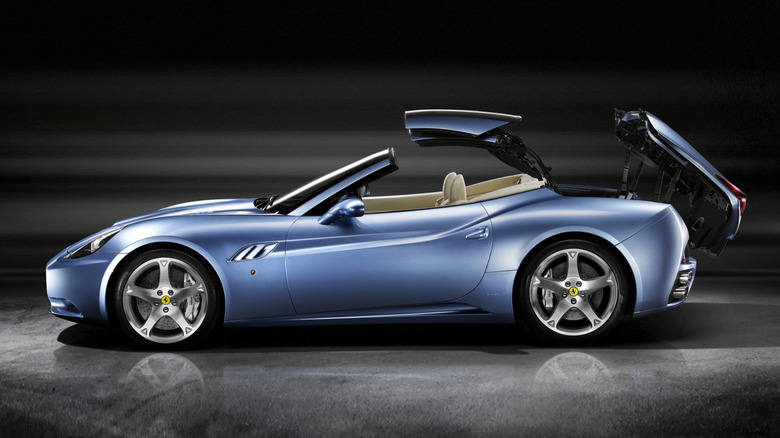 Blue Ferrari California with retractible top mechanism partway open in studio setting