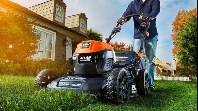 A person using an Atlas lawn mower on grass.