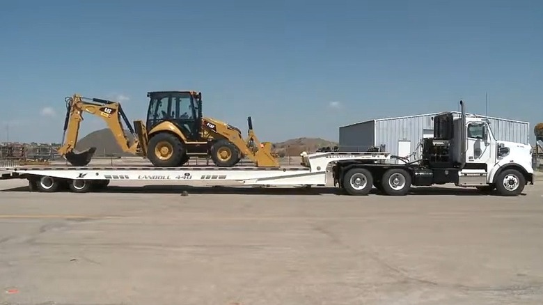 A semi hauling a backhoe loader
