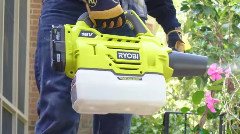 A person using a Ryobi fogger on plants.