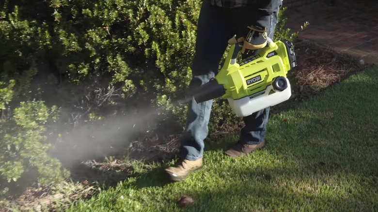 A person using a Ryobi fogger outside.