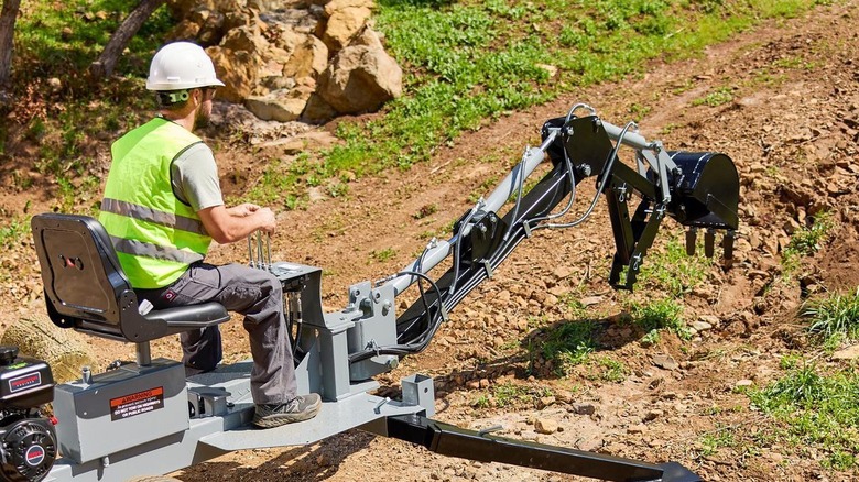 man using towable backhoe