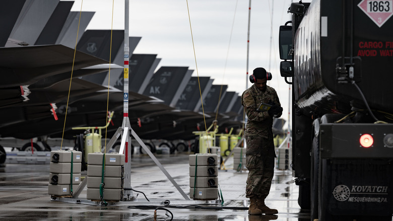 Person checks fuel on truck next to long line of F-35As.