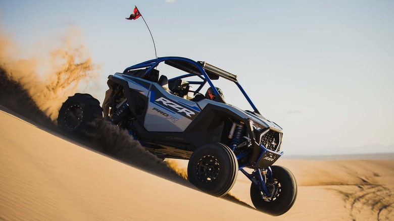 A Polaris RZR Pro R driving down a sand dune