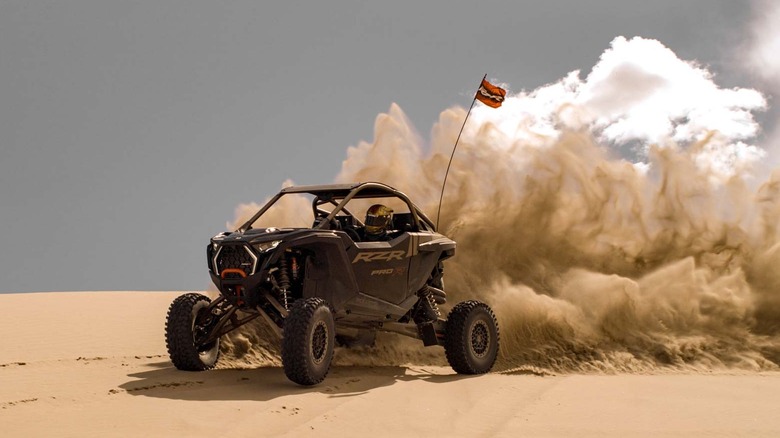 A Polaris RZR Pro R driving over a sand dune