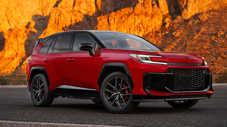 A red 2026 Toyota RAV4 PHEV parked in front of dramatic cliffs at sunset