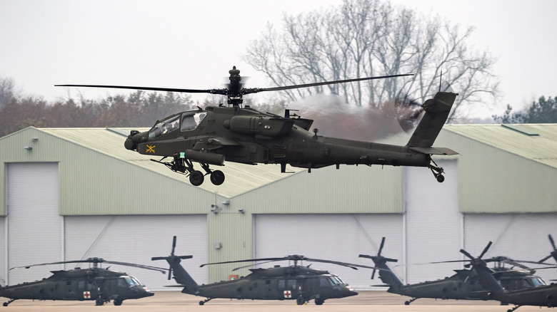 AH-64 Apache Landing con helicópteros Blackhawk en el fondo