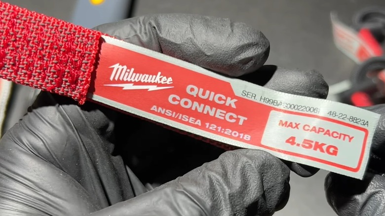 A person holding the label of a Milwaukee tool lanyard.