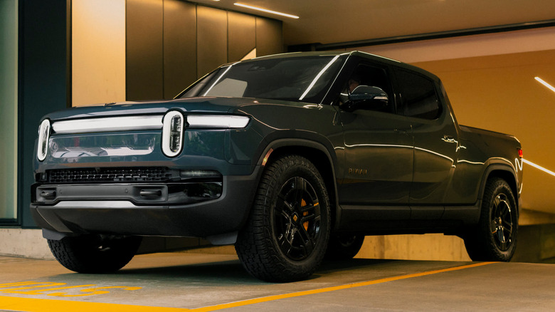 Rivian R1T truck pulling out of a parking garage, front 3/4 view