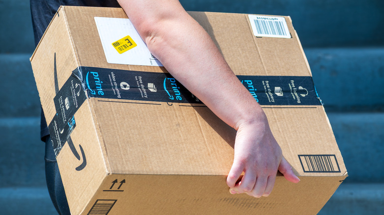 An Amazon driver carries a package for delivery.