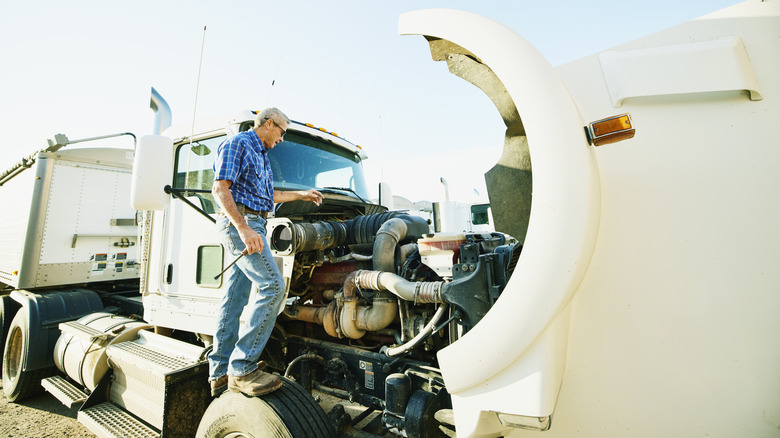 a man repairing his white semi truck