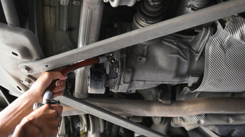 Someone replacing the differential fluid in a car