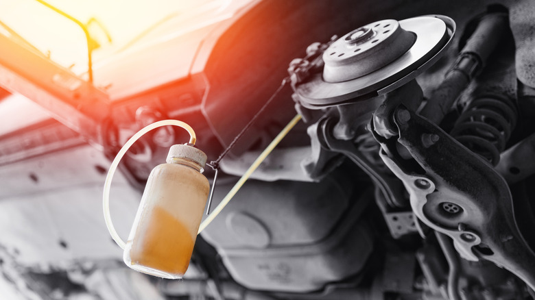 A bottle being used to siphon out remaining brake fluid from a car