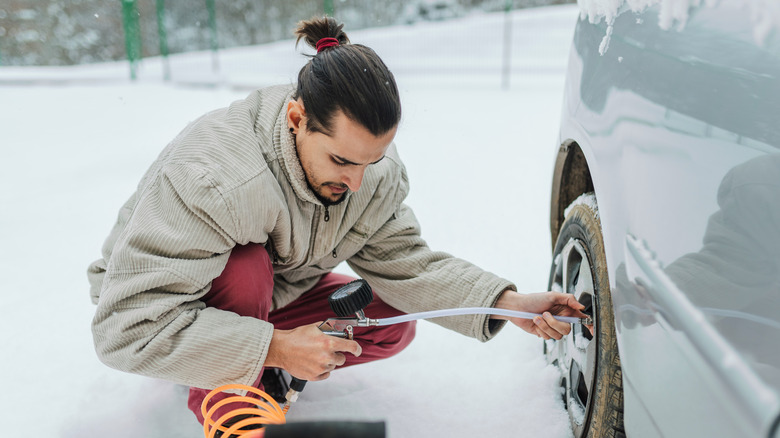 Man checking tire pressure in winter