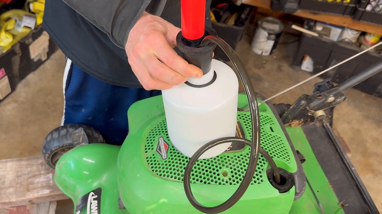 A man extracting used oil out of a lawn mower