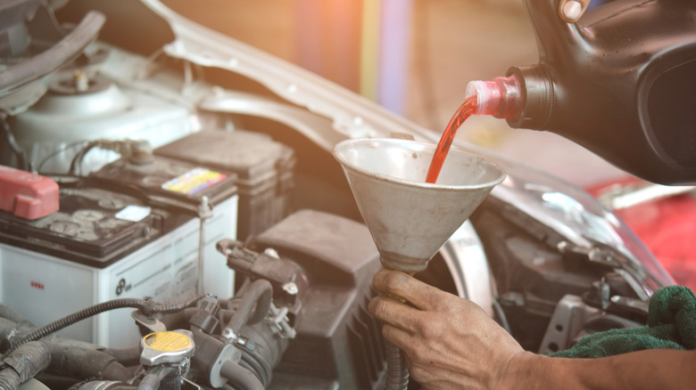 Transmission oil fill up in a car engine using metal cone.