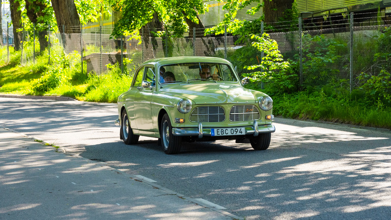 green Volvo Amazon driving on country road, front-right three-quarter view