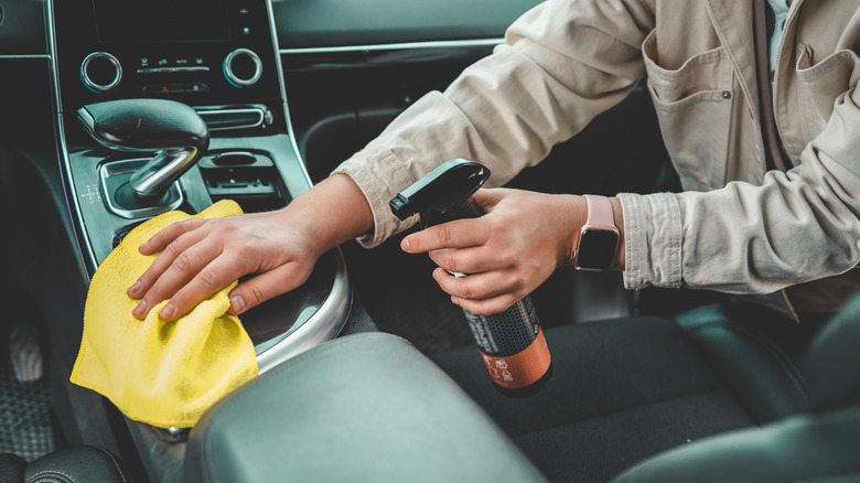 A woman at a car wash does a full dry-cleaning of all parts of a car using special chemistry, cloths, sponges and brushes.