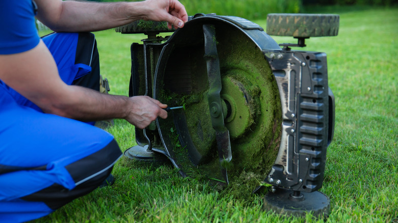 Worker inspecting the underside of a lawn mower