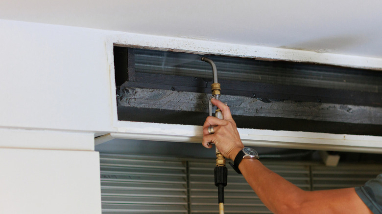 A technician cleaning an air conditioner vent.