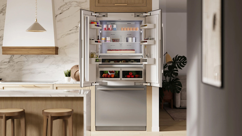 A Bosch French door fridge in a white, brown, and black kitchen.
