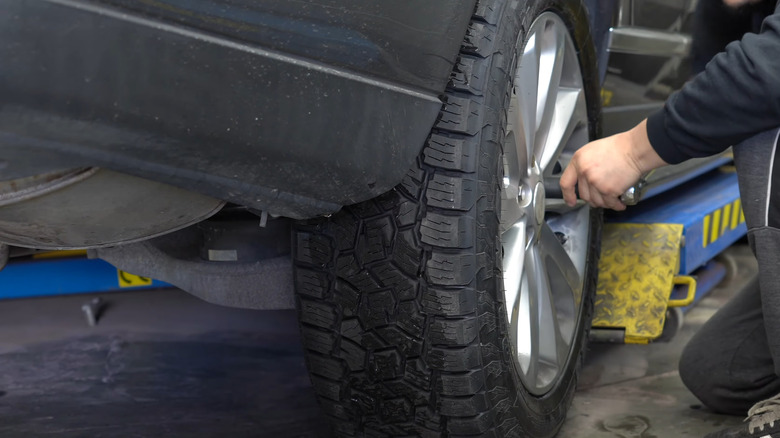 A mechanic mounting Toyo Open Country AT3 tires on a Range Rover