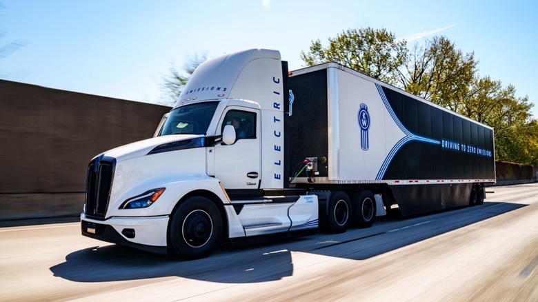 Kenworth T680E driving on a road with trees in the background