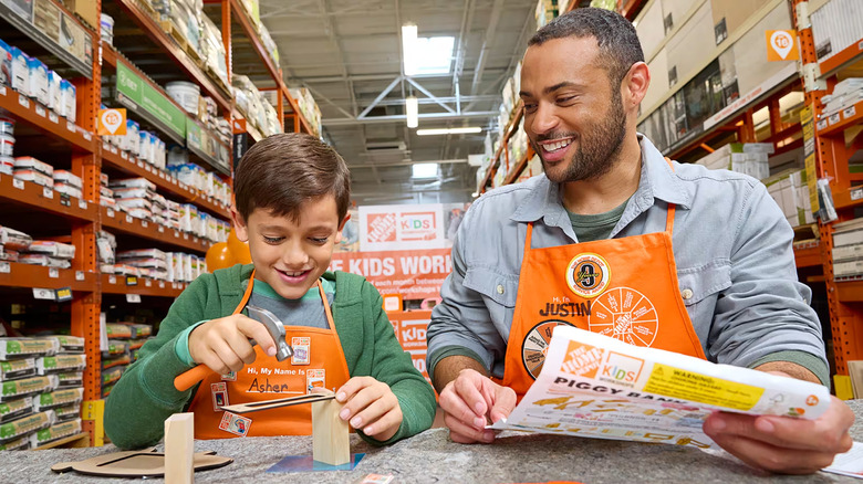 Kid working on wood structure with Home Depot associate
