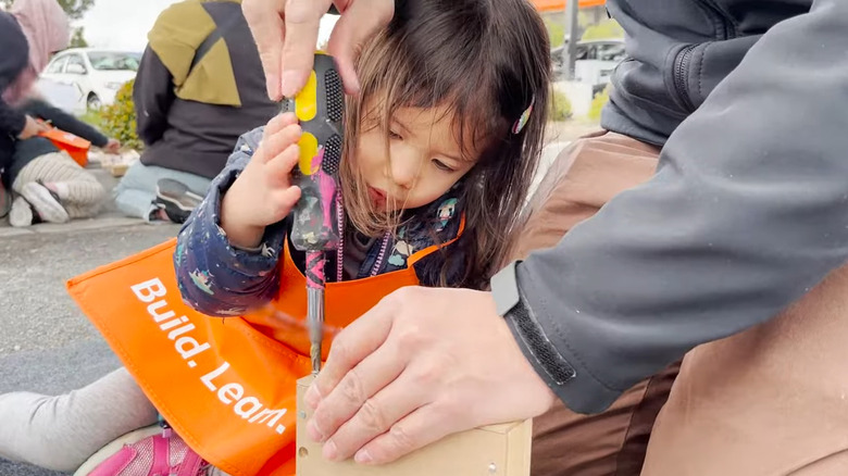 Young girl helping her dad use screwdriver