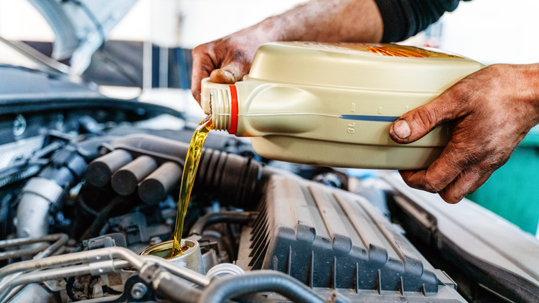 Hands pouring oil into engine