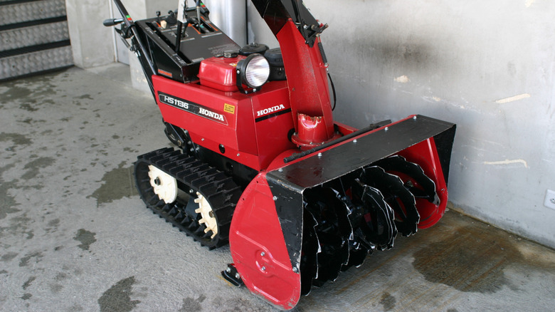 Side view of a red Honda snowblower with tracks