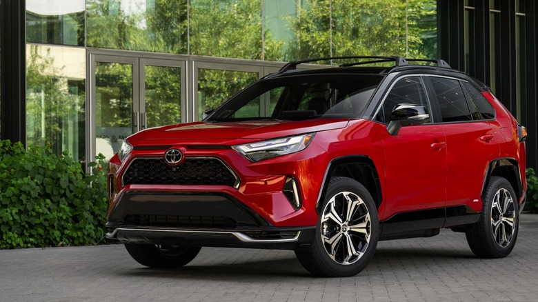 Red Toyota RAV4 Prime Plug-In Hybrid parked in front of a building