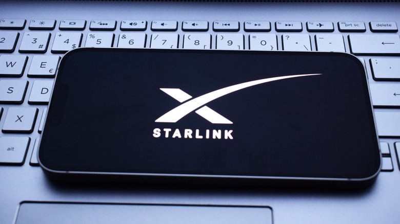 The Starlink logo displayed on a smartphone placed upon a laptop keyboard.