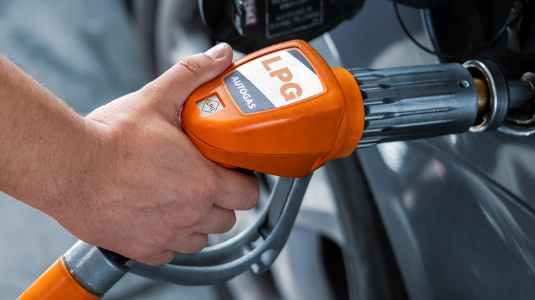 Close-up of a hand holding an LPG nozzle and filling a car up.