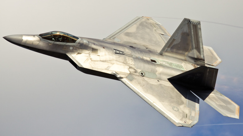 An F-22 soaring through an overcast sky.