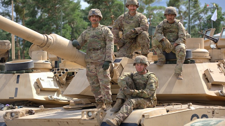 Four U.S. Army tankers standing atop their M1A2 Abrams MBT