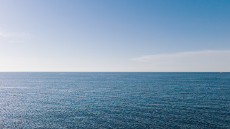 The Sun beginning to set over a clear ocean.