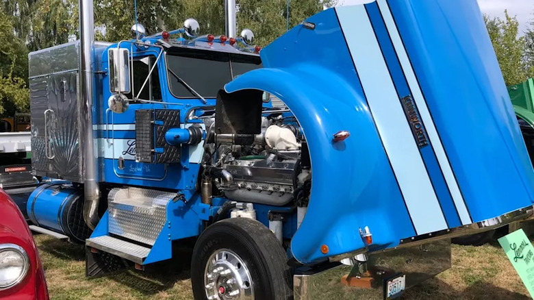 A parked semi truck with the hood open to see a detroit diesel 12V 71 engine