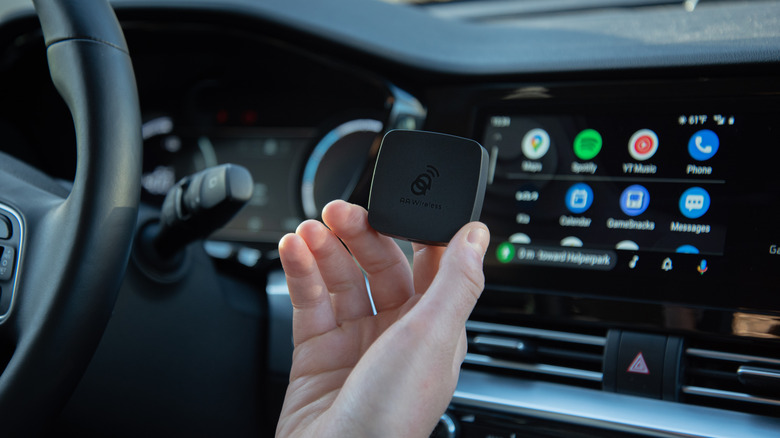 AAWireless Android Auto adapter held in front of dashboard and android auto screen