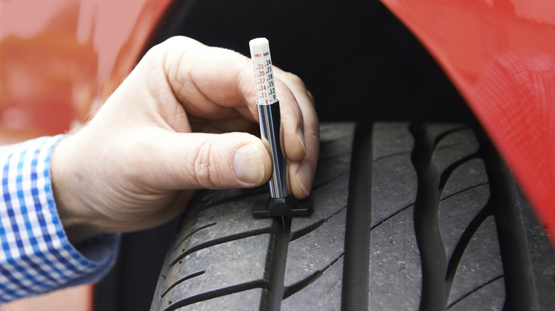A person measuring a tire tread using a specialty tool
