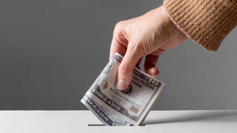 hand dropping cash into box