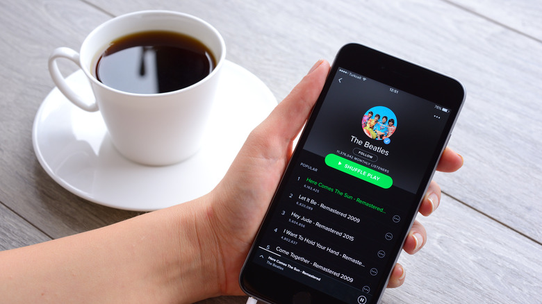 Spotify on phone next to coffee cup
