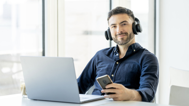 man listening to music with headphones while holding phone