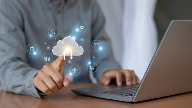 A person using a laptop and touching an imaginary cloud icon