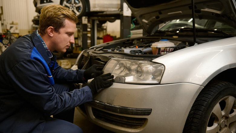 auto mechanic adjusts headlights